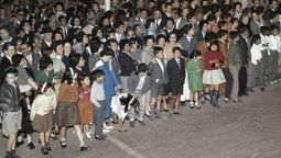 Una multitud esperando a la farándula estudiantil del Día de la Primavera en avenida San Martín. Imagen de principios de la década del 60 mejorada con Gemini.