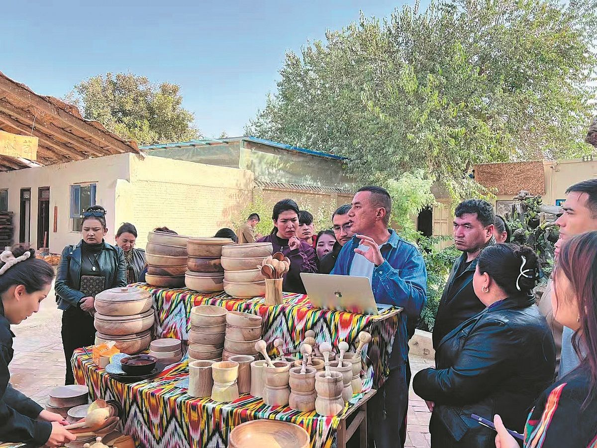 Erxat Ibrayim (tercero desde la derecha) recibe a visitantes en su taller en la prefectura de Hotan, región autónoma uygur de Xinjiang. PARA USO DE CHINA DAILY
