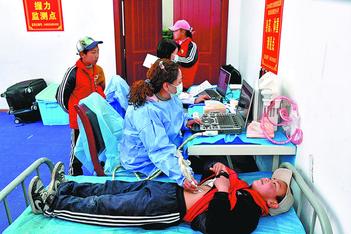 Un estudiante de primaria se somete a una ecografía abdominal para detectar equinococosis durante los chequeos médicos gratuitos financiados por el gobierno para residentes del condado de Chonggyai, región autónoma de Xizang, en marzo. PARA USO DE CHINA DAILY.