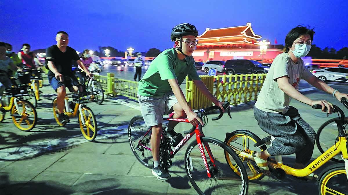 Unos ciclistas pasan por la plaza de Tian’anmen en Beijing en julio durante un paseo nocturno por la avenida Chang’an