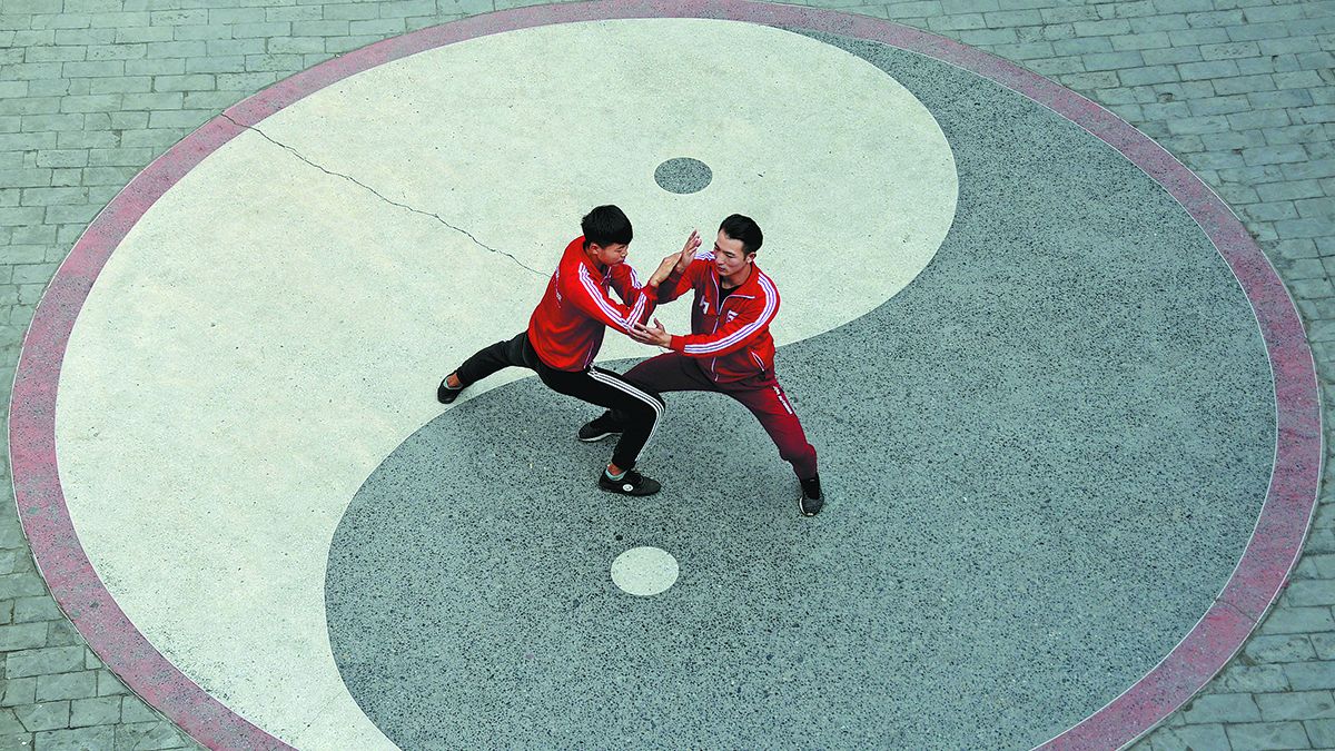 Dos practicantes de taijiquan participan de un entrenamiento sobre un suelo que muestra el patrón del yin y el yang en Chenjiagou