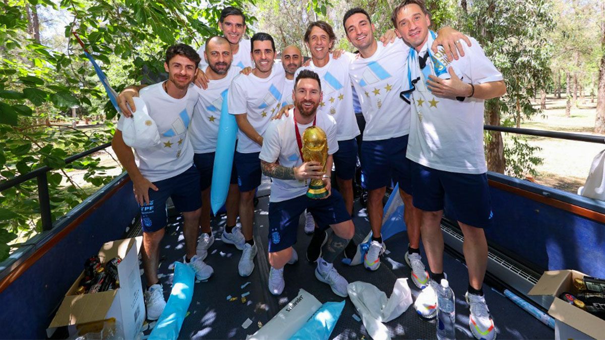 Leo Messi posa con la Copa del Mundo y detrás suyo están Lionel Scaloni y el cuerpo técnico de la Selección argentina.