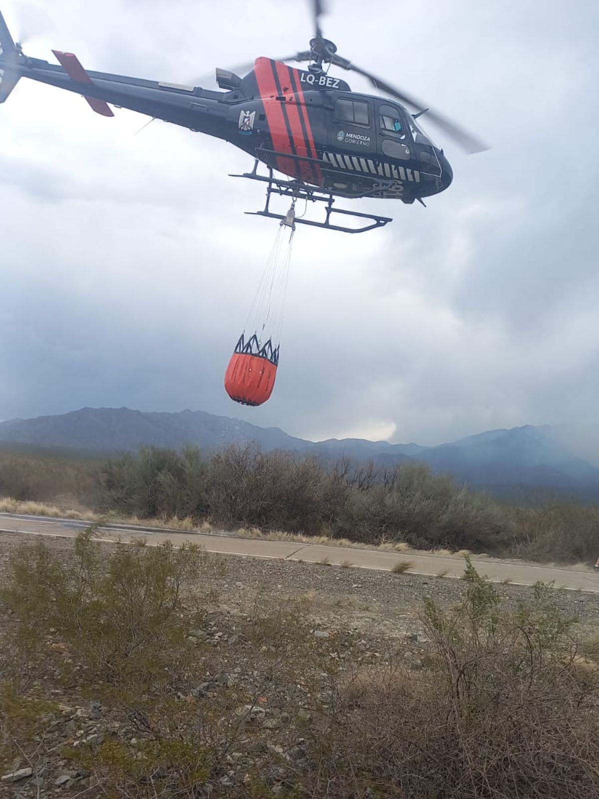 El helicóptero hidrante partiendo con su carga de agua para apagar el incendio en Las Heras.