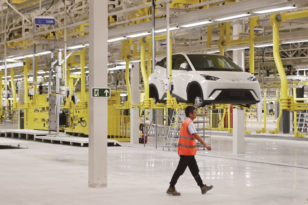 Un miembro del personal pasa junto a un taller en la base de producción del fabricante automotriz chino BYD en Camaçari, estado de Bahía, Brasil. LUCIO TAVORA / XINHUA