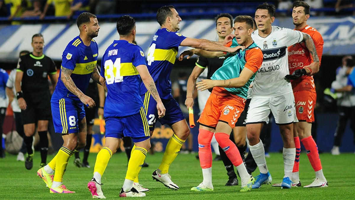 Rodrigo Rey está detrás de sus compañeros del Lobo, quienes lo defienden de los jugadores de Boca.