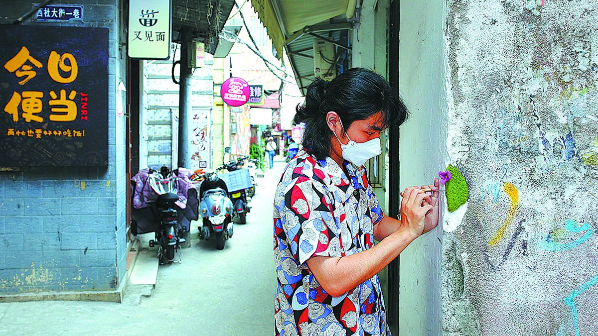 Luo Shengtian coloca una flor de fieltro en la esquina rota de una pared en la aldea de Nanting en Guangzhou