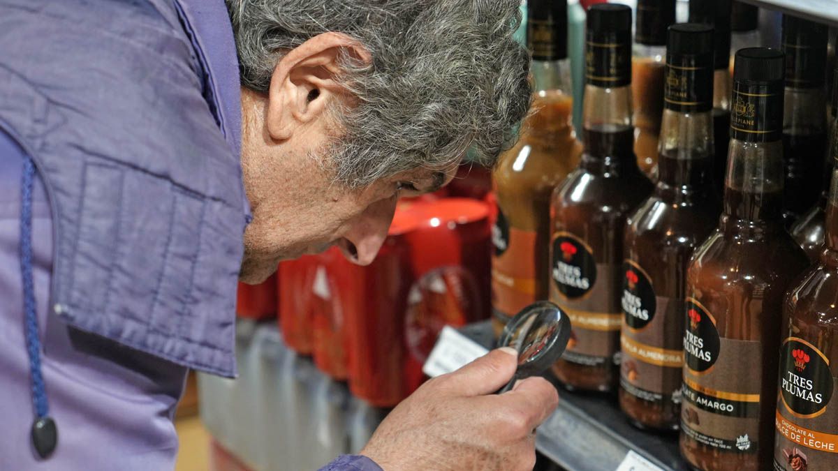 Con lupa, el hombre revisa los precios de los licores.