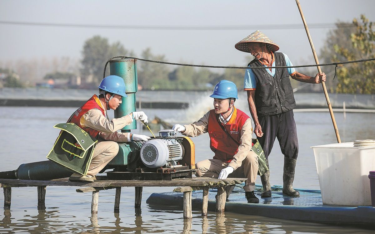 Los trabajadores de la energía eléctrica inspeccionan equipos de suministro de oxígeno en un estanque de cangrejos en Huai’an