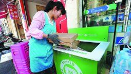 Una mujer arroja cajas de entrega vacías en un contenedor de reciclaje en una comunidad en Kunming, provincia de Yunnan. PARA USO DE CHINA DAILY